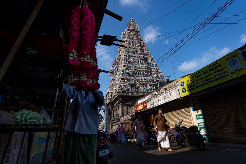 Flower vendors set up their shops as devotees walk outside Mylapore temple in the southern Indian city of Chennai, April 15, 2024. Southern India is home to some of the country's most visited temples and has millions of Hindu devotees. What sets it apart, experts say, is that religion hasn't been weaponized for political gain. (AP Photo/Altaf Qadri)