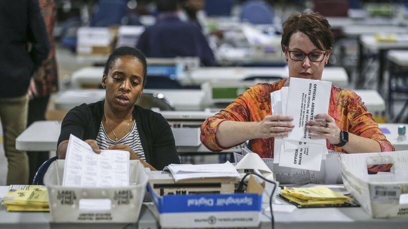 Elections Coordinator Shantell Black (left) and Elections Deputy Director Kristi Royston open and scan absentee ballots on Nov. 7, 2018 at the Voter Registration and Elections Office in Lawrenceville. JOHN SPINK/JSPINK@AJC.COM