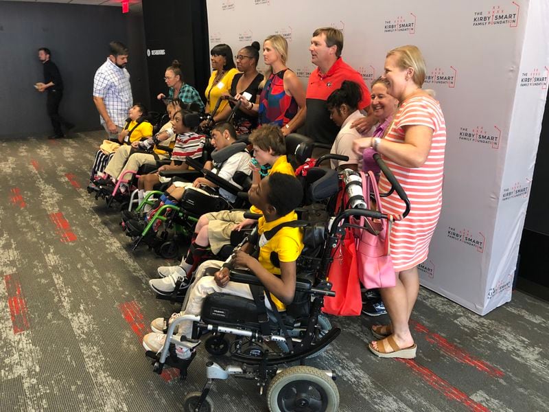 Kirby and Mary Beth Smart (back row, center, in red) pose Wednesday with children and their parents who benefit from the Kirby Smart Family Foundation.