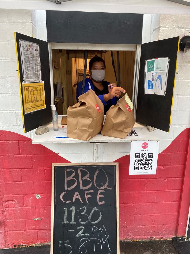 BBQ Cafe’s Sabirah Rasheed hands a to-go order out the window of the takeout-only spot in downtown Decatur. Wendell Brock for The Atlanta Journal-Constitution