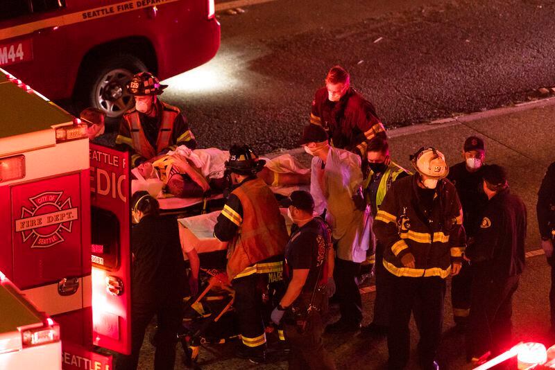 Emergency workers bring an injured person to an ambulance after a driver sped through a protest-related closure on the Interstate 5 freeway in Seattle, authorities said early Saturday, July 4, 2020. Dawit Kelete, 27, has been arrested and booked on two counts of vehicular assault. (James Anderson via AP)