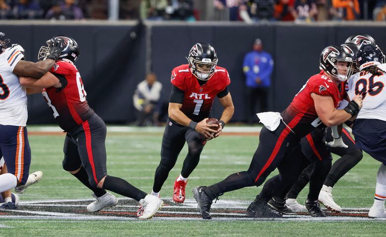 Falcons quarterback Marcus Mariota runs for a short gain with help from guard Chris Lindstrom and center Drew Dalman during the third quarter Sunday against the Bears.  The Falcons won 27-24. (Bob Andres / for The Atlanta Journal-Constitution)