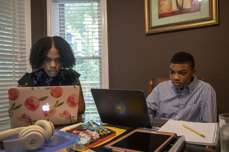 Cassidy Valbrun, left, homeschool’s her nephew Malachi Battle at the kitchen table at their residence in Grayson on May 18, 2021. Cassidy, a rising senior at Kennesaw State University, has been teaching Malachi ever since February when he was suspended from Couch Middle School for an alleged ‘Zoom Bombing’ during a virtual class. (Alyssa Pointer / Alyssa.Pointer@ajc.com)