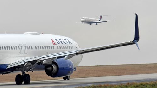 A Delta Air Lines jet prepares to take off as another jet approaches at Hartsfield-Jackson International Airport. HYOSUB SHIN / HSHIN@AJC.COM