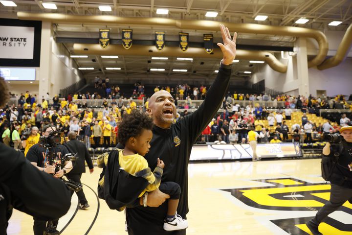 Kennesaw State Owls head coach Amir Abdur-Rahim waves to the fans as he carries his son after the 88-81 victory over the Liberty Flames at the Kennesaw State Convention Center on Thursday, Feb 16, 2023. 
 Miguel Martinez / miguel.martinezjimenez@ajc.com