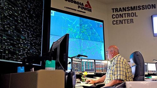 Gerald Snodgrass sits in front of the large electronic mimic board (left), which displays the status of transmission lines and substations around the state, and a smaller screen (right) which shows the Southern Company load flow from Mississippi to the Florida panhandle, at the Georgia Transmission Control Center at Georgia Power.