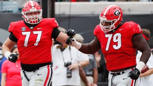 Georgia offensive linemen Cade Mays (77) and Isaiah Wilson (79) fist bump after Georgia wide receiver Jeremiah Holloman (9) scored the Bulldogs' first TD on Saturday, Oct. 27, 2018, at TIAA Bank Field in Jacksonville, FL. BOB ANDRES / BANDRES@AJC.COM