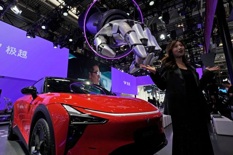 A woman reacts near the 01 from Jiyue-auto during Auto China 2024 in Beijing, Thursday, April 25, 2024. Global automakers and EV startups unveiled new models and concept cars at China's largest auto show on Thursday, with a focus on the nation's transformation into a major market and production base for digitally connected, new-energy vehicles. (AP Photo/Ng Han Guan)