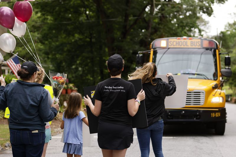 Parents and students hold signs and balloons to surprise Atlanta Public Schools bus driver Alma Jennings as she pulled up to their stop on her route on Monday, May 23, 2022. (Natrice Miller / natrice.miller@ajc.com)