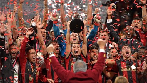 Atlanta United midfielder Miguel Almiron (center) raises the MLS Cup as they celebrate after their 2-0 win over the Portland Timbers during the 2018 MLS Cup at Mercedes-Benz Stadium on Saturday, December 8, 2018. HYOSUB SHIN / HSHIN@AJC.COM