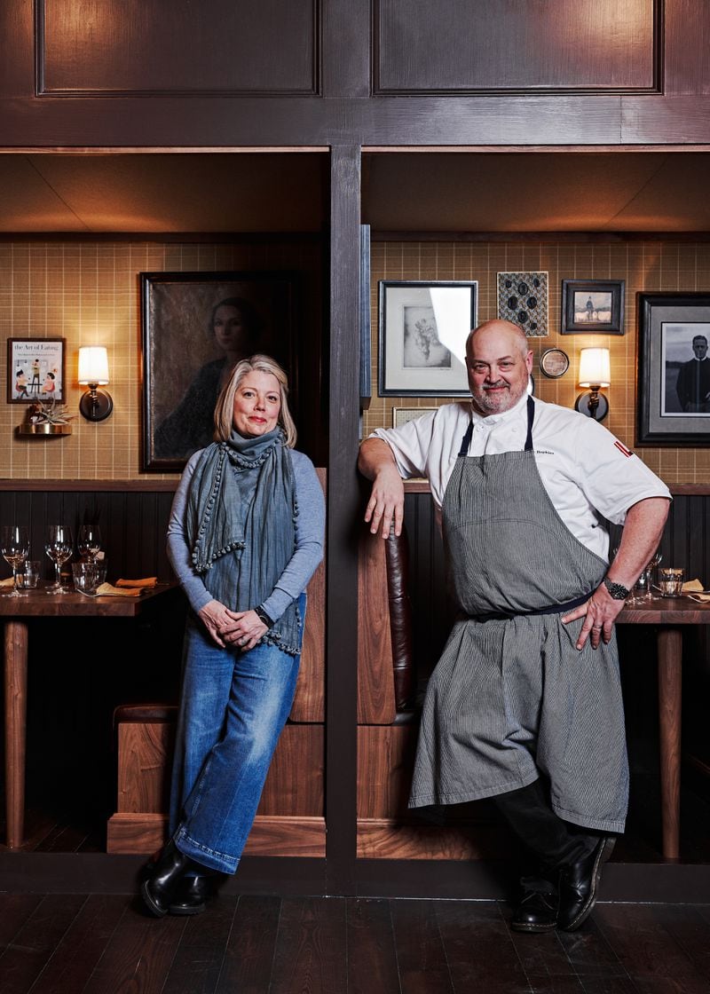 Gina and Chef Linton Hopkins stand in Holeman and Finch in front of a painting of a socialite found in a New York antique shop.  Each of the 9 booths at Holeman and Finch have a curated selection of art that is personal to the Hopkinses. / Courtesy of Holeman & Finch