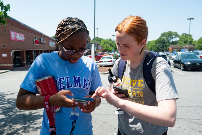 Spelman student Sommer Madison, left, and Georgia Tech student Meg Sanders set up an app to map temperature data from a Bluetooth device as they walk near the Westside Beltline on Wednesday, June 15, 2022. (Ben Gray for the Atlanta Journal-Constitution)