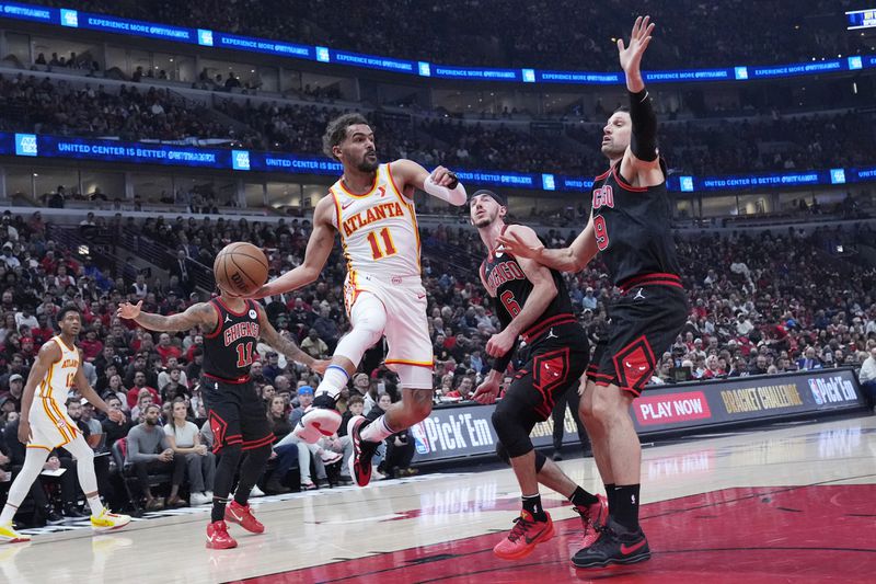 Atlanta Hawks guard Trae Young (11) looks to pass the ball as Chicago Bulls guard Alex Caruso and center Nikola Vucevic, right, defend during the first half of an NBA basketball play-in tournament game in Chicago, Wednesday, April 17, 2024. (AP Photo/Nam Y. Huh)