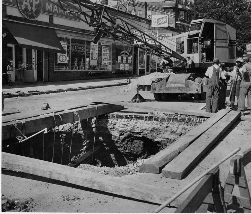 Workers fill a huge chasm under Ponce de Leon Avenue in 1955. The cavity at Penn Avenue extended 42 1/2 feet below the street and was 25 feet in diameter.
