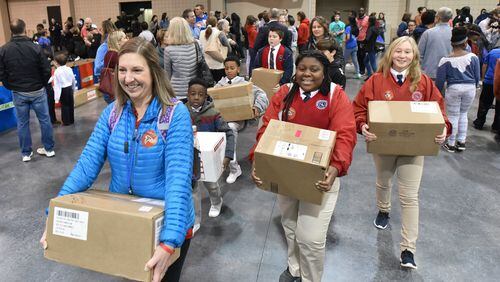 Christine Krabel (foreground), a teacher from Our Lady of Victory School in Tyrone, and her students bring in their donations during the NFL’s Super Kids-Super Sharing project at the Infinite Energy Forum in Duluth. The project started in Atlanta in 2000 and celebrates its 20th anniversary in Atlanta. HYOSUB SHIN / HSHIN@AJC.COM