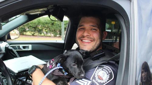 Sgt. Aaron Thacker with the Rome Police Department cuddles with a little pooch from Floyd County PAWS who rode along with him for the Law Dog for a Day program. (Courtesy of Floyd County Sheriff's Office)