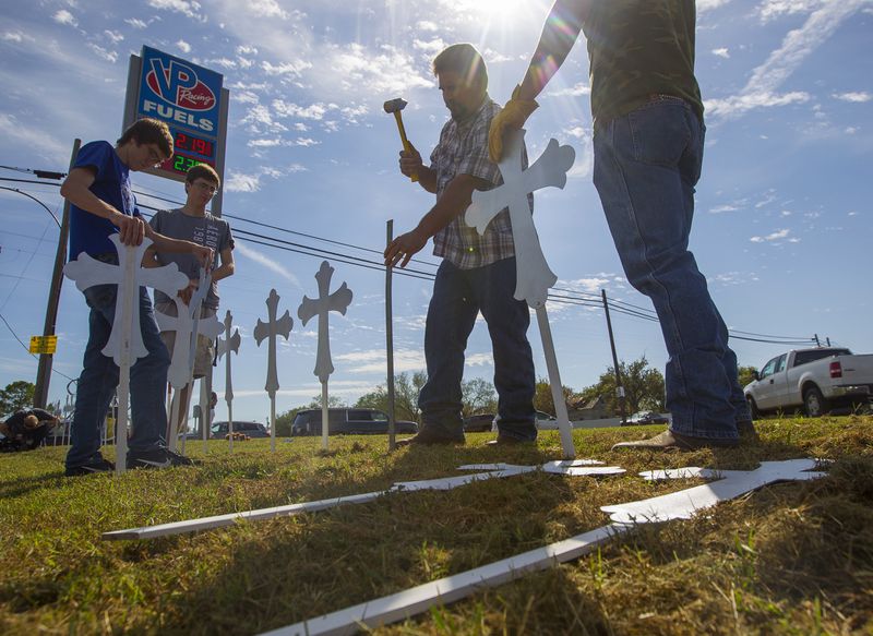 Doug John, of La Vernia, Texas, hammers in crosses at the VP Racing Fuels gas station just down the road from the First Baptist Church of Sutherland Springs, Monday, Nov. 6, 2017, in Sutherland Springs, Texas. John made the crosses last night with apprentices in a sheet metal workers Local 67 apprenticeship program. "If it can happen in Sutherland Springs, Texas, it can happen anywhere," said John of the mass shooting on Sunday at the church. (Mark Mulligan/Houston Chronicle via AP)
