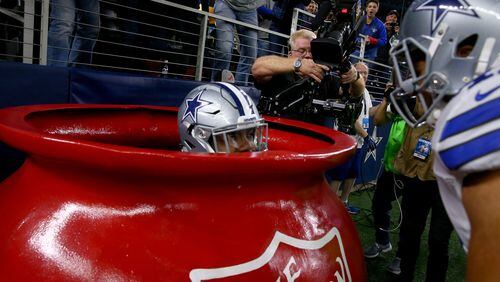 Ezekiel Elliott #21 of the Dallas Cowboys celebrates after scoring a touchdown by jumping into a Salvation Army red kettle during the second quarter against the Tampa Bay Buccaneers at AT&T Stadium on December 18, 2016 in Arlington, Texas.