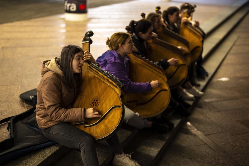 Ukrainian Kobza music band members play traditional "bandura" instruments in a passage under the Independence square in central Kyiv, Saturday, April 20, 2024. (AP Photo/Francisco Seco)