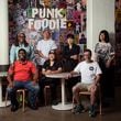 Punk Foodie founder Sam Flemming (front row right) with pop-up chefs at the Punk Foodie stall at Ponce City Market including (left to right) Jimmie Jackson and Phya J. of JJC Jimmie Jerk Chicken;  Fu-Mao Sun of Mighty Hans and Jess Kim (center seated) and Jun Park (standing) of Ganji; Sam Flemming of Punk Foodie; Designer Alynn Martinez .   (MARTHA WILLIAMS FOR THE ATLANTA JOURNAL-CONSTITUTION)