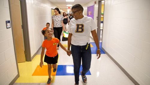 Beecher Hills Elementary school principal Crystal Jones (R) walks down the hall while holding the hand of Olivia Sorel during the first open house after the schools’ extensive renovation Friday, August 9, 2019.STEVE SCHAEFER / SPECIAL TO THE AJC