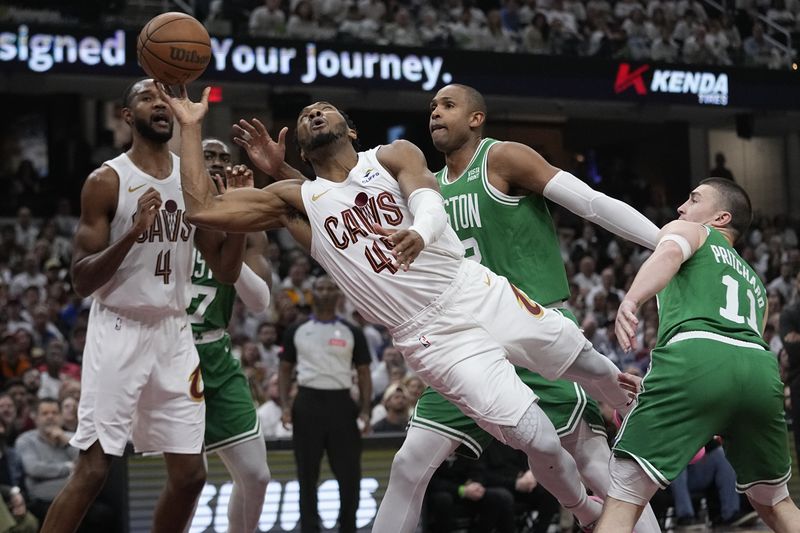 Cleveland Cavaliers guard Donovan Mitchell (45) is fouled as he goes to the basket between Boston Celtics center Al Horford, second from right, and guard Payton Pritchard (11) during the first half of Game 3 of an NBA basketball second-round playoff series Saturday, May 11, 2024, in Cleveland. (AP Photo/Sue Ogrocki)