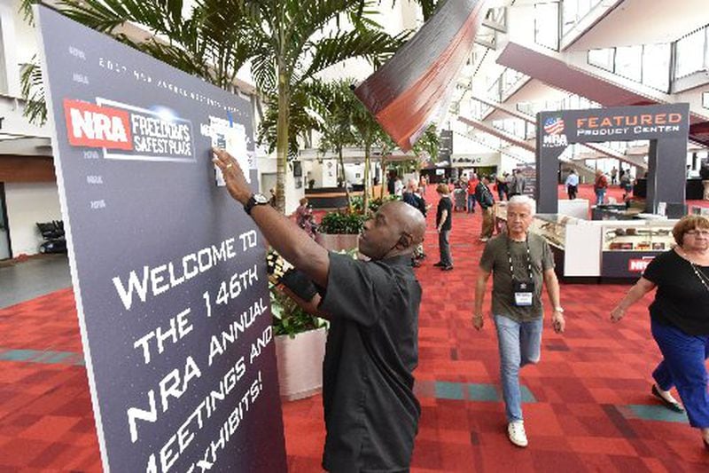 Donovan Holtzclaw sets up a banner at the Georgia World Congress Center in preparation for the NRA convention. HYOSUB SHIN / HSHIN@AJC.COM