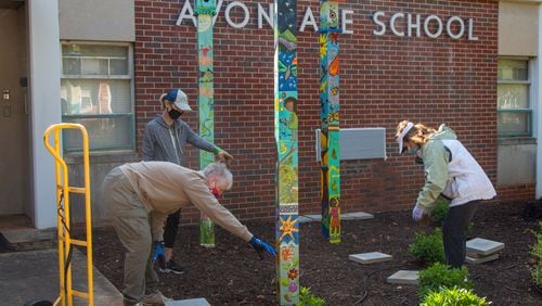 Co-chair Carolyn Chandler (clockwise from bottom left), Jennifer Houpt and Carolyn Adams place stepping stones around three hand-painted totem poles in the new garden area in front of Avondale Elementary School which also features a lending library. The Avondale Estates Garden Club and the Avon Garden Club worked together on the project.
PHIL SKINNER FOR THE ATLANTA JOURNAL-CONSTITUTION.