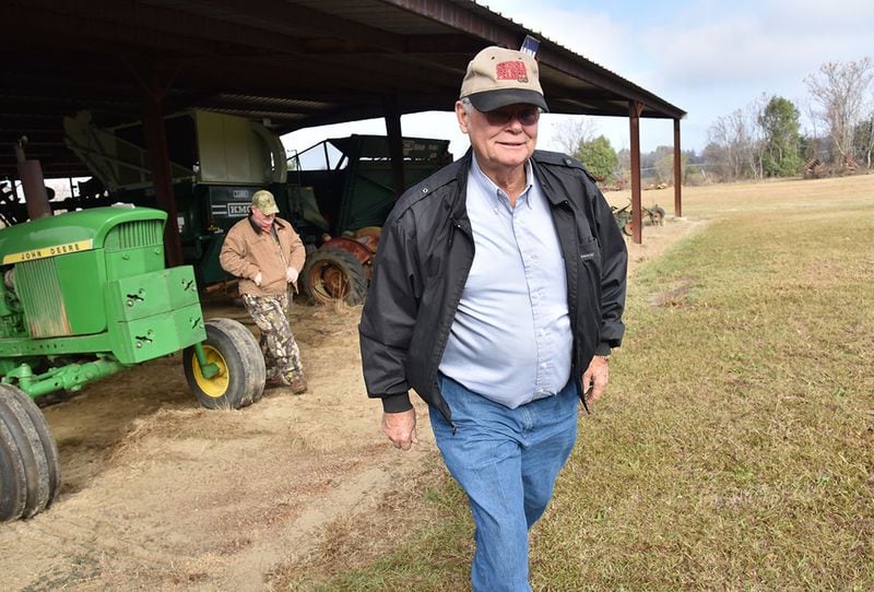 Rex Bullock and his employee David McDuffie (background) check utility tractors at his farm. Bullock, a model of self-reliance, bought his first new tractor -- the John Deere seen here -- in 1969. When it began to wear out several years ago, he rebuilt it and gave it a new coat of paint. "I don't like to get rid of things," he says. HYOSUB SHIN / HSHIN@AJC.COM