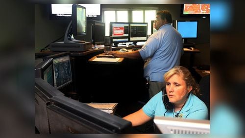 Communications Officers Chad Jenkins and Michelle Schneider handle calls in the Roswell Police 911 Center in 2010. AJC FILE PHOTO