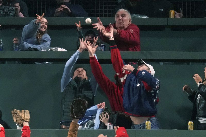 Fans reach for the ball on a solo home run by Boston Red Sox's Connor Wong against the Cleveland Guardians during the fourth inning of a baseball game Wednesday, April 17, 2024, in Boston. (AP Photo/Charles Krupa)