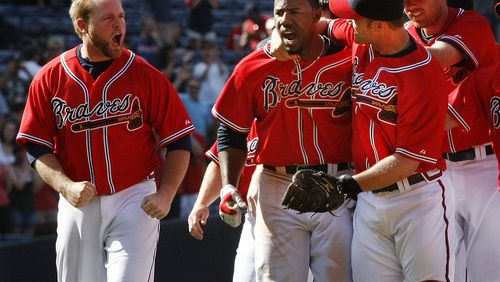 Braves catcher Brian McCann, left, cheers on (22) Jason Heyward, center as he is mobbed by David Ross and the rest of the Braves team after hitting a game winning single to score Martin Prado in the 9th for a 4-3 victory over the Rockies at Turner Field in Atlanta.