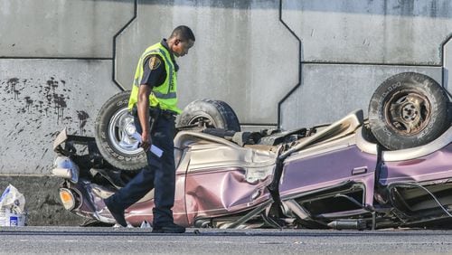 College Park police investigate the scene of an accident the morning of April 9. The northbound lanes of I-85 and the exit ramp at Riverdale Road backed up following a fatal wreck involving a sport utility vehicle that police said fell 15 feet off adjacent I-285. (JOHN SPINK / JSPINK@AJC.COM)