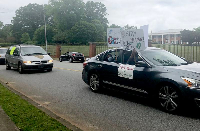 Protesters drive past the Governor's Mansion carrying signs and honking horns Friday. (Photo: Greg Bluestein/AJC)