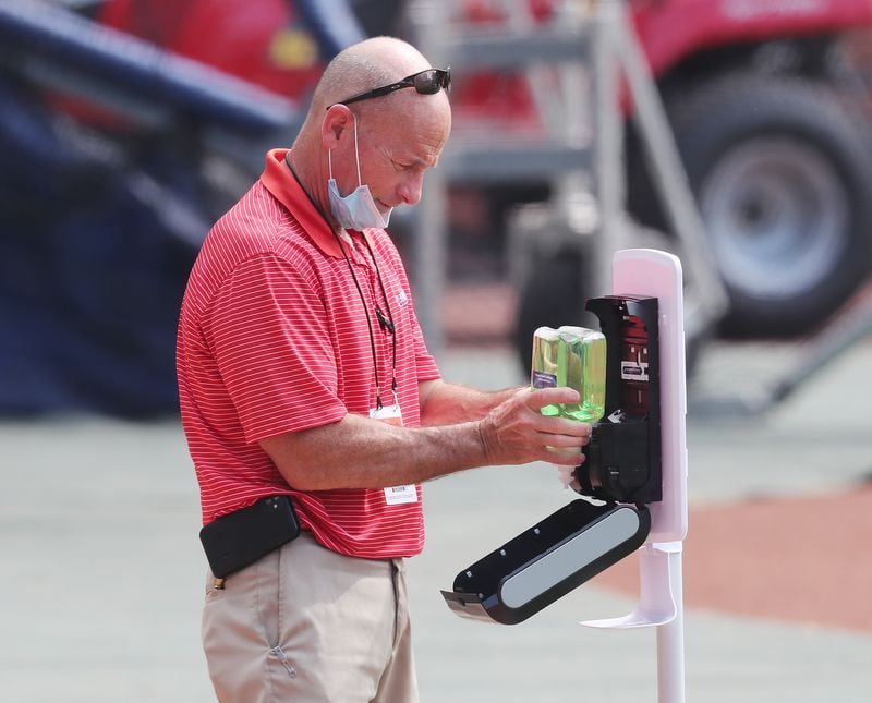 Braves senior director of field operations Ed Mangan sets up a hand sanitizer station for players and coaches by the dugout.  Curtis Compton ccompton@ajc.com