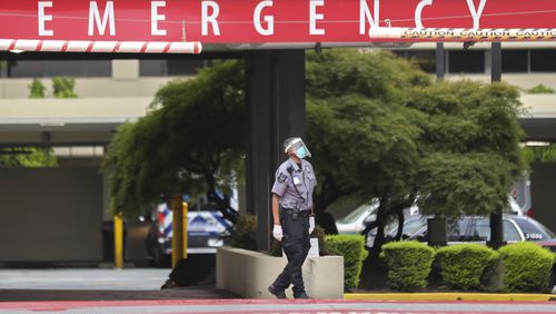 A security guard waits at the emergency entrance at Wellstar Atlanta Medical Center on Boulevard in Atlanta on Wednesday. In five of Georgia's 14 hospital regions, ICUs were over 100 percent capacity, as of Tuesday night. That left patients across the state waiting in Emergency Departments for a critical-care bed, or remaining in rural hospitals even though they needed to be transferred for higher-level care. Meanwhile, ambulance drivers routinely waited for hours outside hospitals, tending to their patients until space opened up for them to be transported inside. (John Spink / John.Spink@ajc.com)