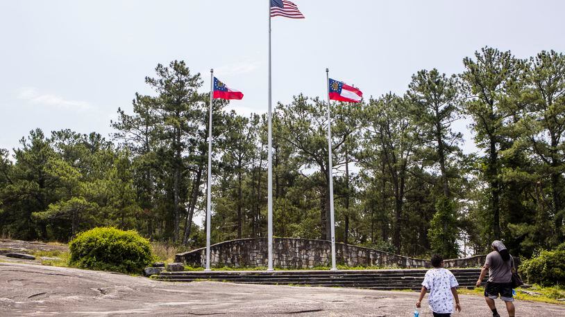 Avery (left) and Cory (right) hike toward where two Georgia state flags and one American flag fly on the Stone Mountain Park walking trail on Friday, May 26, 2023, in Stone Mountain, Georgia. Georgia state flags replaced Confederate flags that used to fly at the spot. CHRISTINA MATACOTTA FOR THE ATLANTA JOURNAL-CONSTITUTION