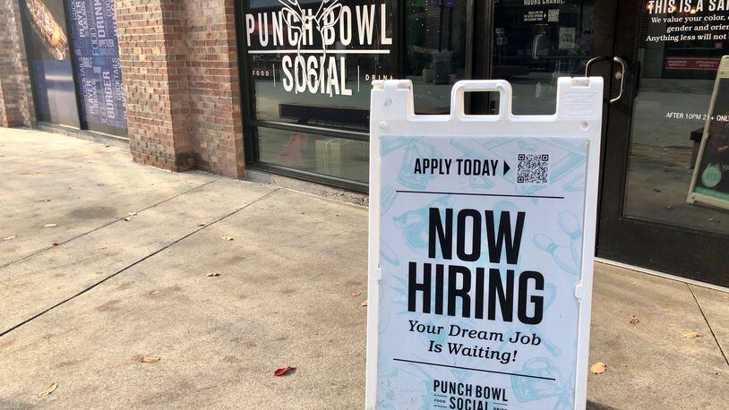 A "now hiring" sign outside Punch Bowl Social at the Battery at Truist Park in early December 2022.