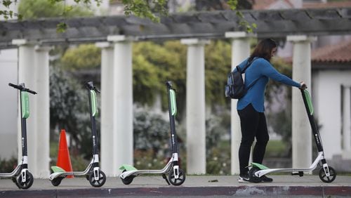 A patron uses her app to unlock a Lime-S electric scooter on Tuesday, April 10, 2018 at Lake Merritt off Grand Avenue in Oakland, Calif. (Laura A. Oda/Bay Area News Group/TNS)