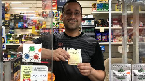 Hamid Rafie, who works at Akers Mill Food Mart, holds a Powerball ticket. Is it the winner? SHEILA POOLE / SHEILA .POOLE@AJC.COM