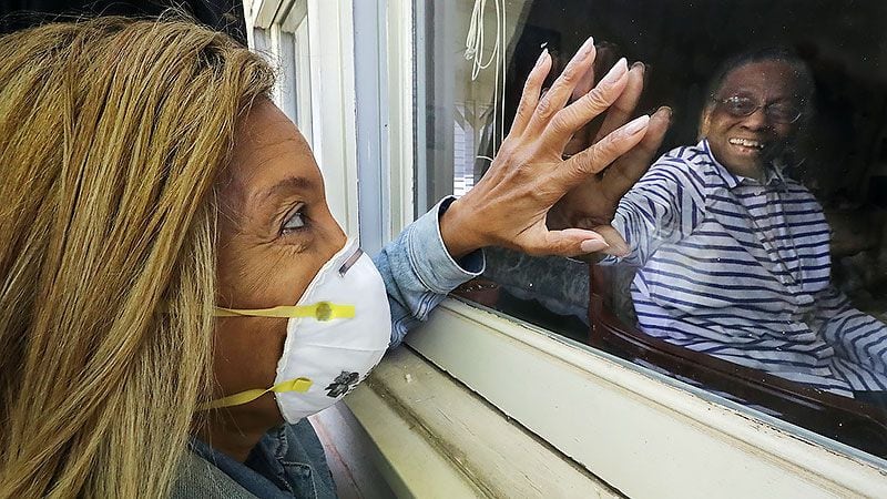 Camilla White visits her mother Lillian Barber, 90, from outside seeing her through the window while touching fingertips through the glass at Cottage Landing Assisted Living in April in Carrollton. (Curtis Compton / ccompton@ajc.com)