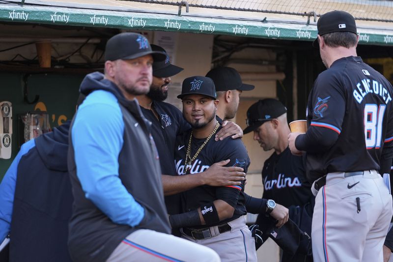 Miami Marlins' Luis Arraez, center, is hugged by a teammate in the dugout after being traded to the San Diego Padres before the team's baseball game against the Oakland Athletics, Friday, May 3, 2024, in Oakland, Calif. (AP Photo/Godofredo A. Vásquez)