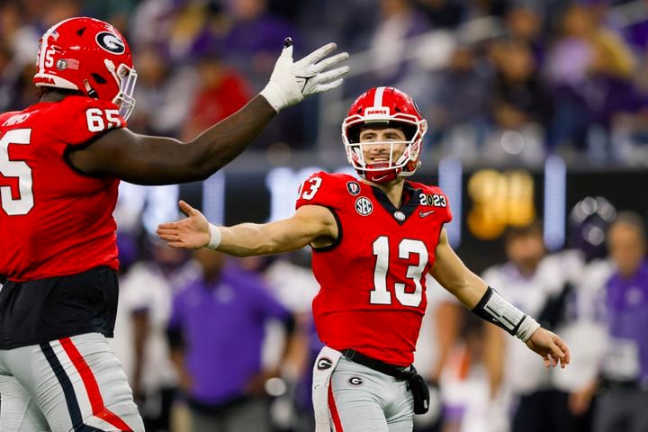 Georgia Bulldogs quarterback Stetson Bennett (13) celebrates a score against the TCU Horned Frogs with lineman Amarius Mims (65) during the second half of the College Football Playoff National Championship at SoFi Stadium in Los Angeles on Monday, January 9, 2023. Georgia won 65-7 and secured a back-to-back championship. (Jason Getz / Jason.Getz@ajc.com)