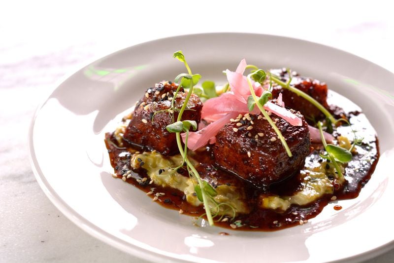 An order of Peppered Pork Belly at City Pharmacy brings fatty, salty chunks glistening with a sorghum glaze over a pool of creamed leeks. CONTRIBUTED BY CITY PHARMACY