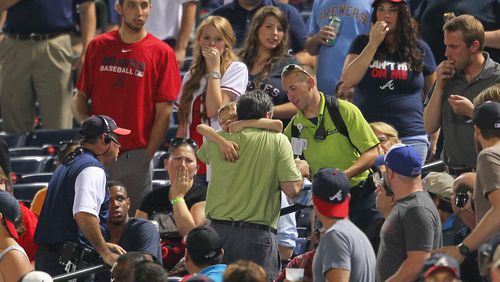 In this Tuesday, May 20, 2014 photo, fans react as a young boy is picked up by his father and rushed up the steps after being hit by a foul ball off the bat of Milwaukee Brewers' Carlos Gomez in the seventh inning of a baseball game against the Atlanta Braves in Atlanta. The 8-year-old boy who was struck in the head has been released from the hospital and is "doing well." While the family requested privacy and boy's name was not released, the Braves said Thursday they had received a call from the victim. He thanked the players who visited him in the hospital and let the team "know that he's home and doing well." (AP Photo/Todd Kirkland)