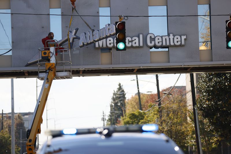 Crew members work removing the signs out of the bridge from the Atlanta Medical Center on Tuesday.. The doors to Atlanta Medical Center downtown were locked Tuesday at midnight. Miguel Martinez / miguel.martinezjimenez@ajc.com