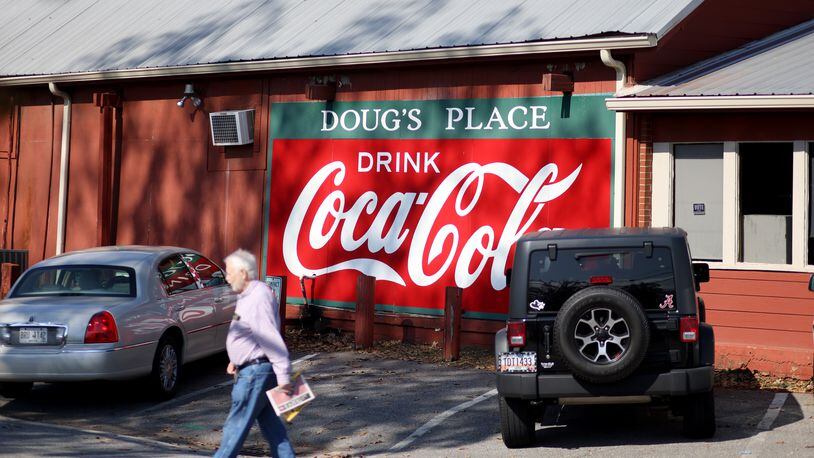 A customer walks by the Coca-Cola sign at Doug’s Place, a meat and three restaurant, on Old Allatoona Road, Thursday, November 3, 2022, in Emerson, Ga. (Jason Getz / Jason.Getz@ajc.com)
