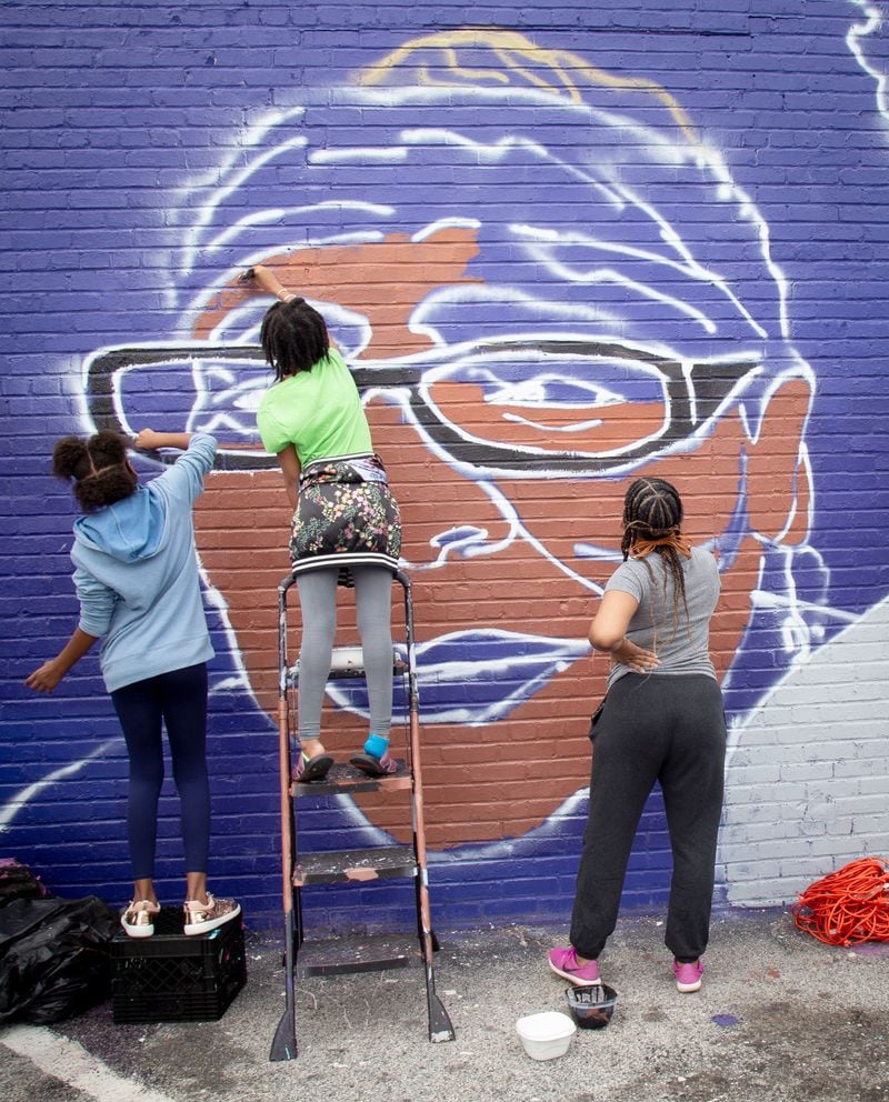 Volunteers from the neighborhood help fill in the details on the "Heroine" mural in Atlanta. STEVE SCHAEFER / FOR THE AJC 