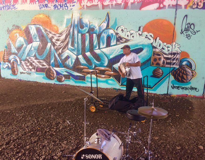 Kermit Walker, who does some drumming along the Beltline under the Freedom Parkway bridge, recently watched a street artist put up a mural.