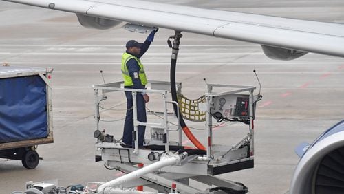 A member of a Delta ground crew prepares a jet for departure at Hartsfield-Jackson International Airport. Delta admits to opposing some environment-friendly measures in a new report.  HYOSUB SHIN / HSHIN@AJC.COM